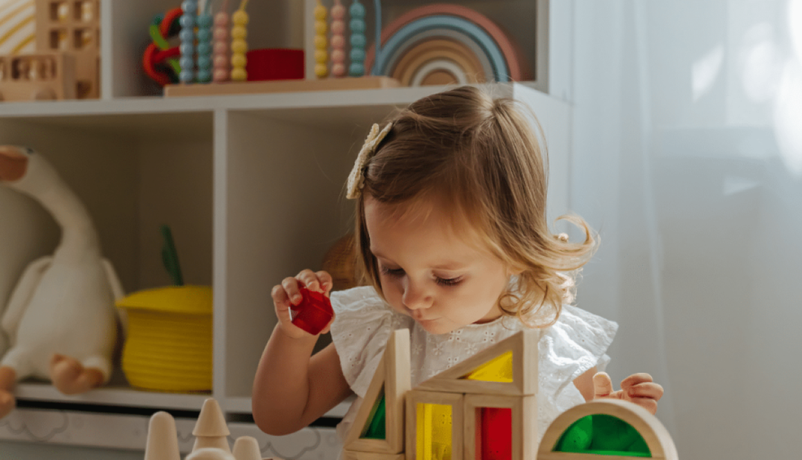 little-girl-playing-with-wooden-blocks-on-the-table-in-playroom